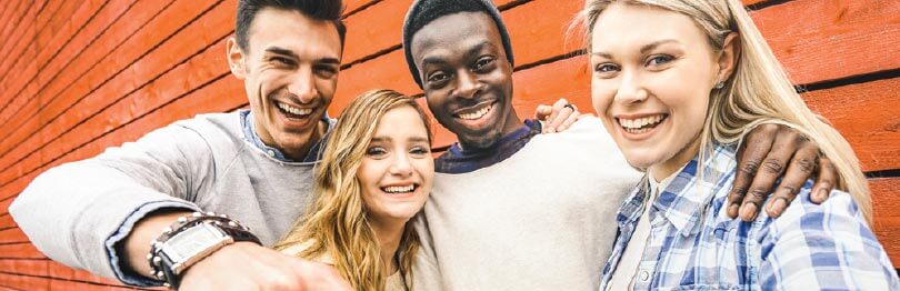 A group of four older teens pose for a picture outside